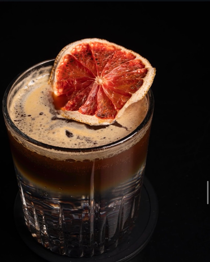 Bebida de autor en vaso facetado con rodaja de naranja deshidratada.