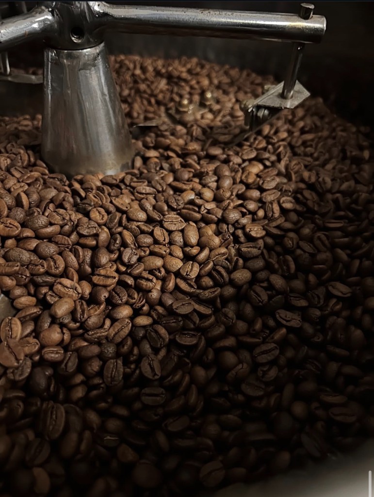 Granos de café recién tostados en tambor de tostadora profesional.
